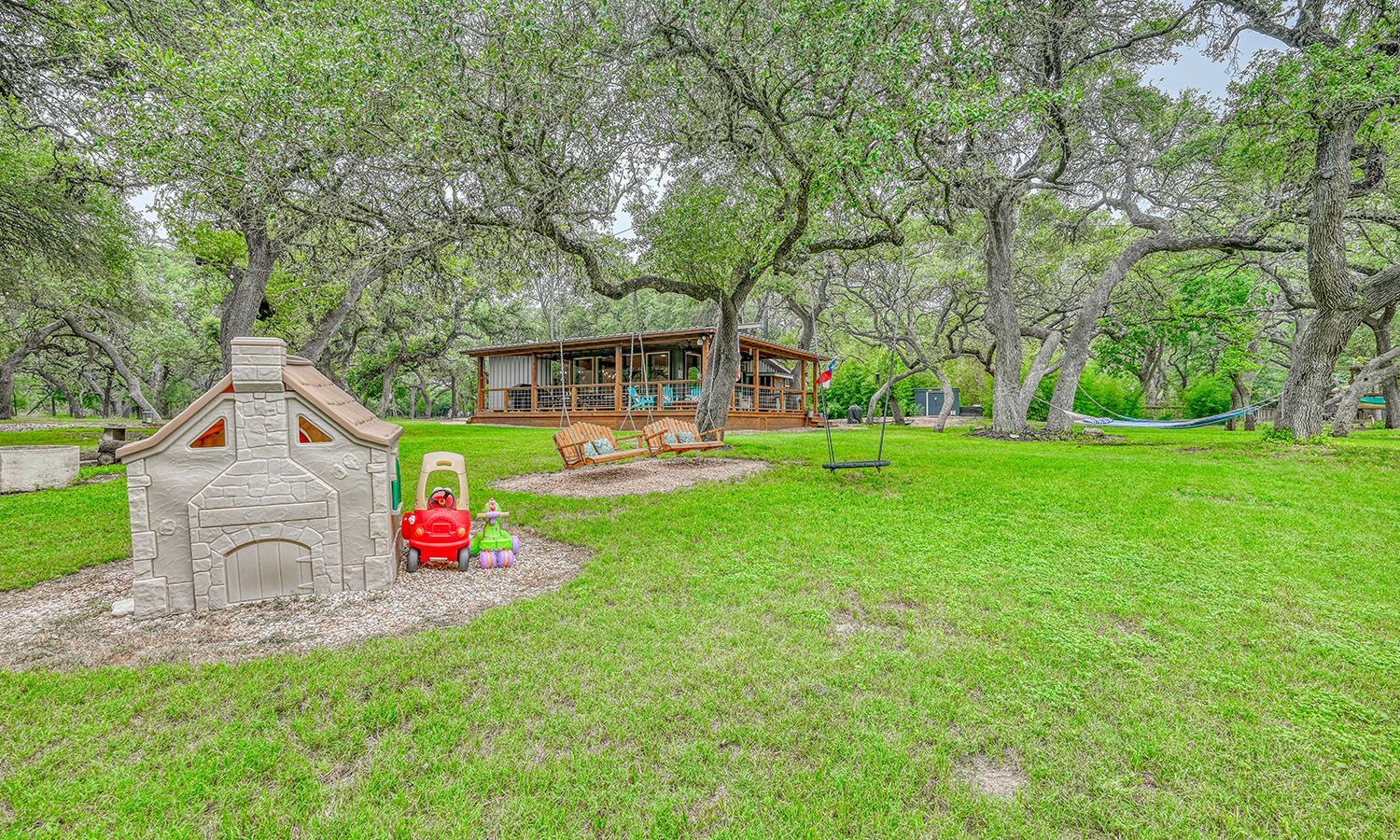 There is a playground in the middle of a lush green field.