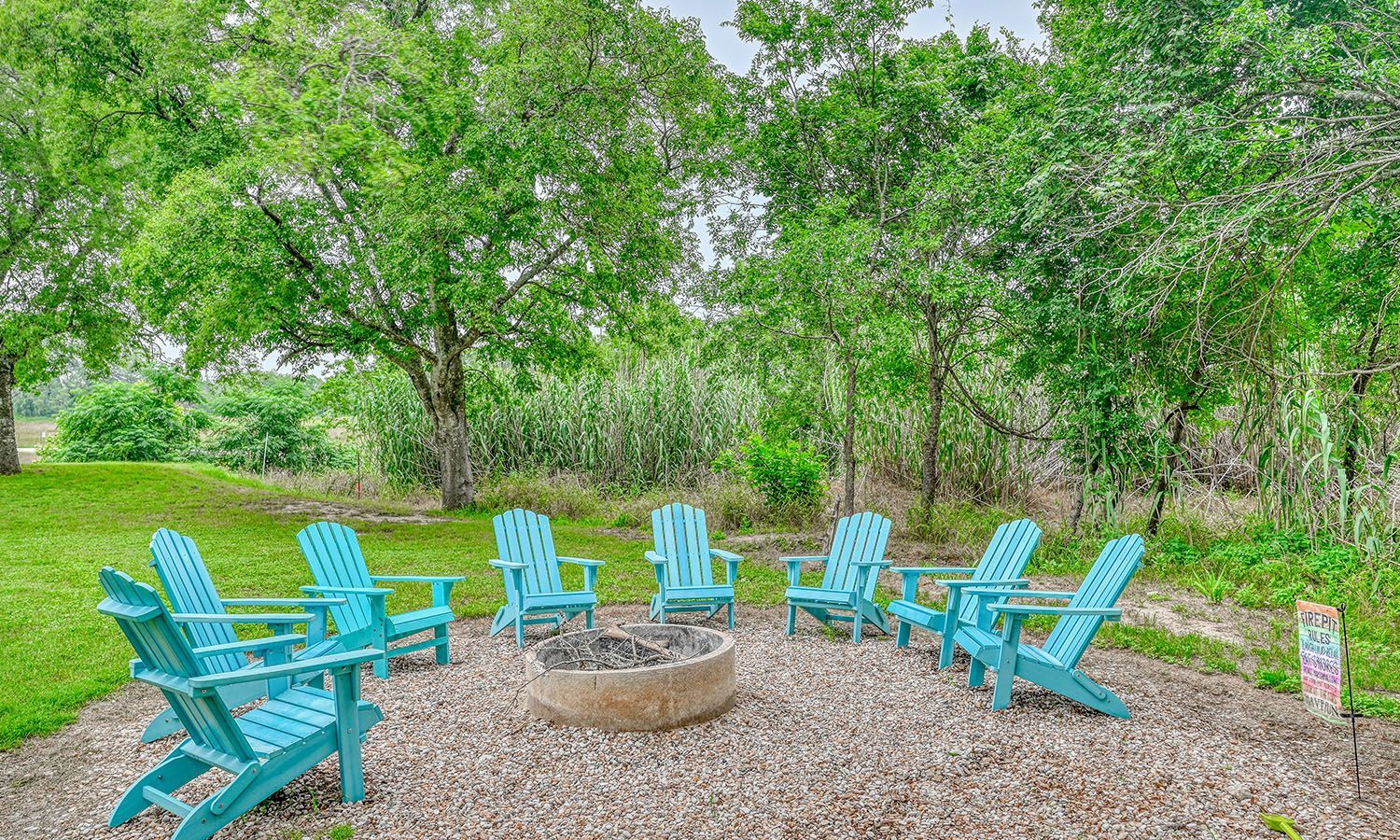 A group of blue chairs are sitting around a fire pit.