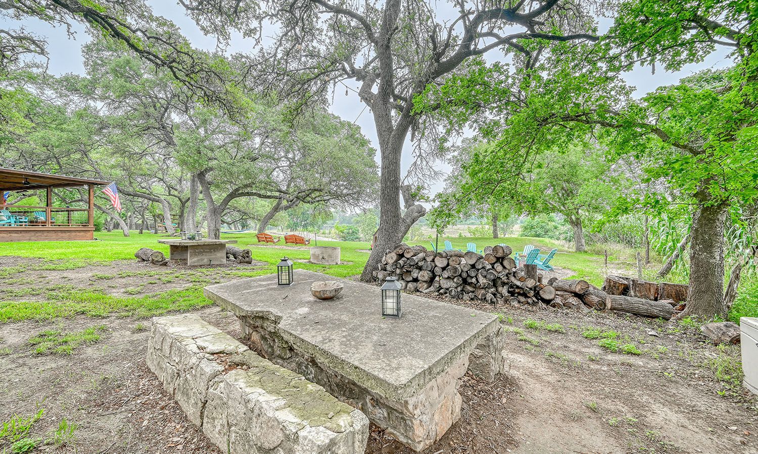 A stone picnic table is sitting under a tree in a field.