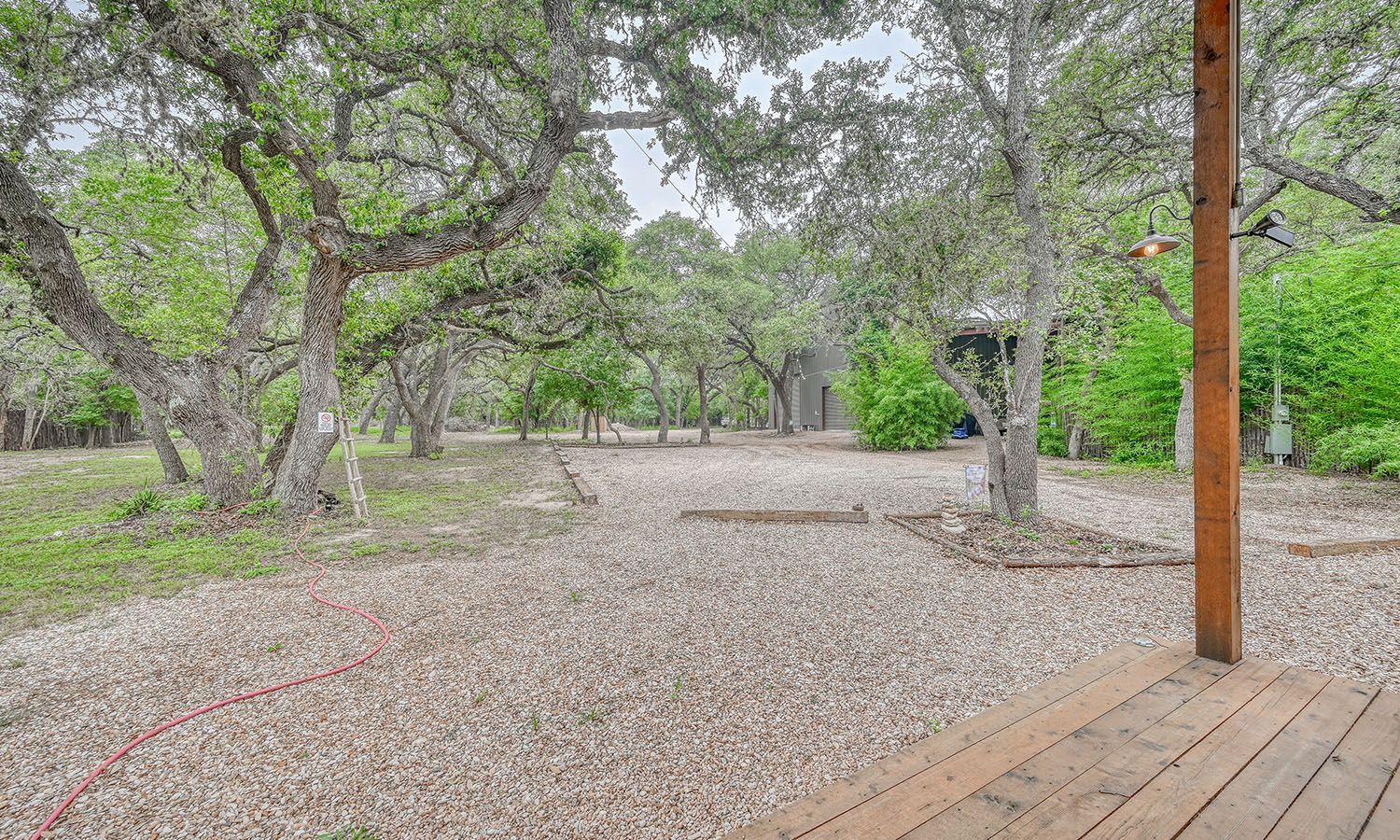 A wooden deck overlooking a gravel driveway surrounded by trees.