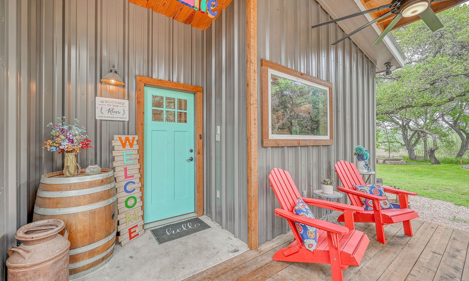 There are two red chairs on the porch of a house.