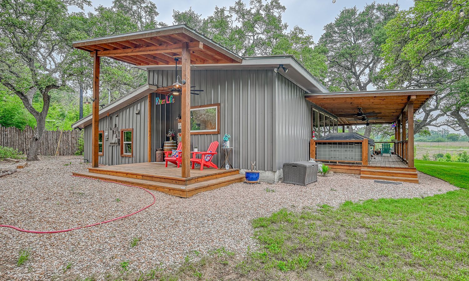 A small house with a porch and red chairs in the backyard.
