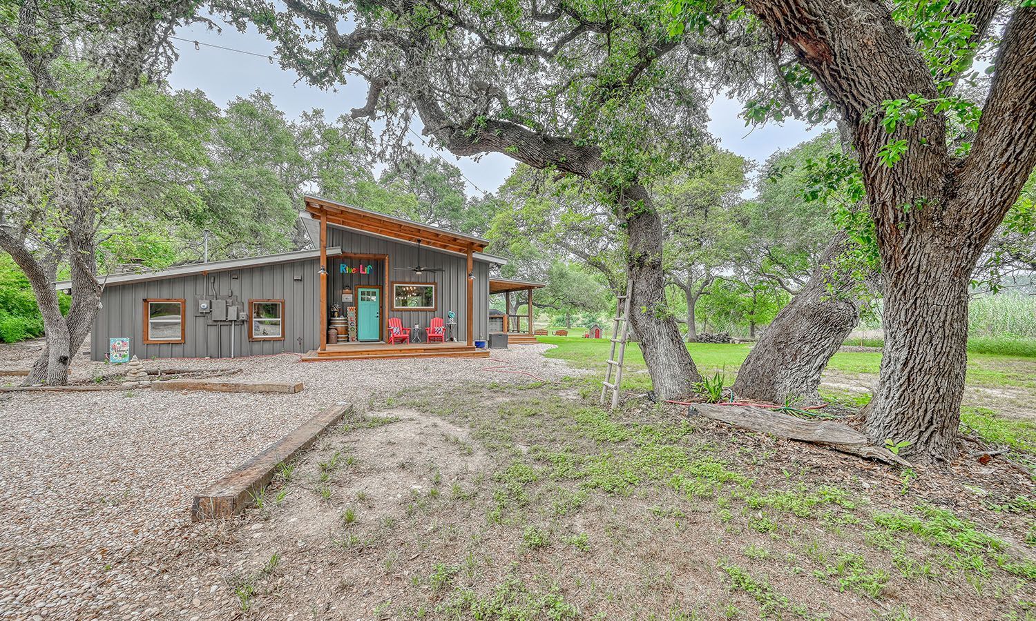 A small house is sitting in the middle of a field surrounded by trees.