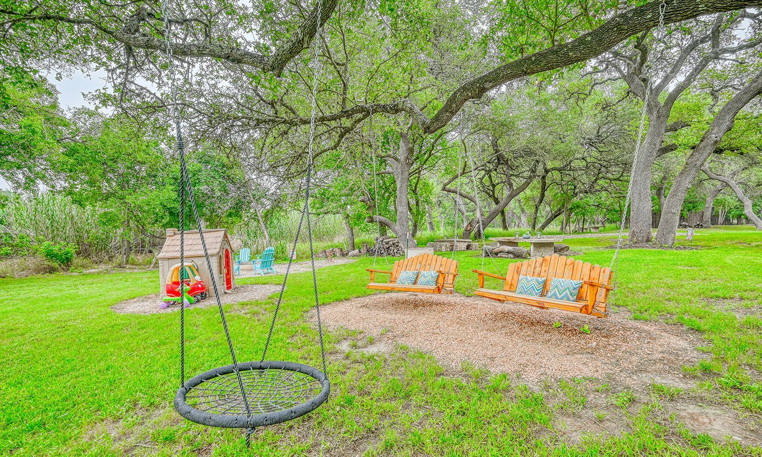A swing is hanging from a tree in the middle of a grassy field.