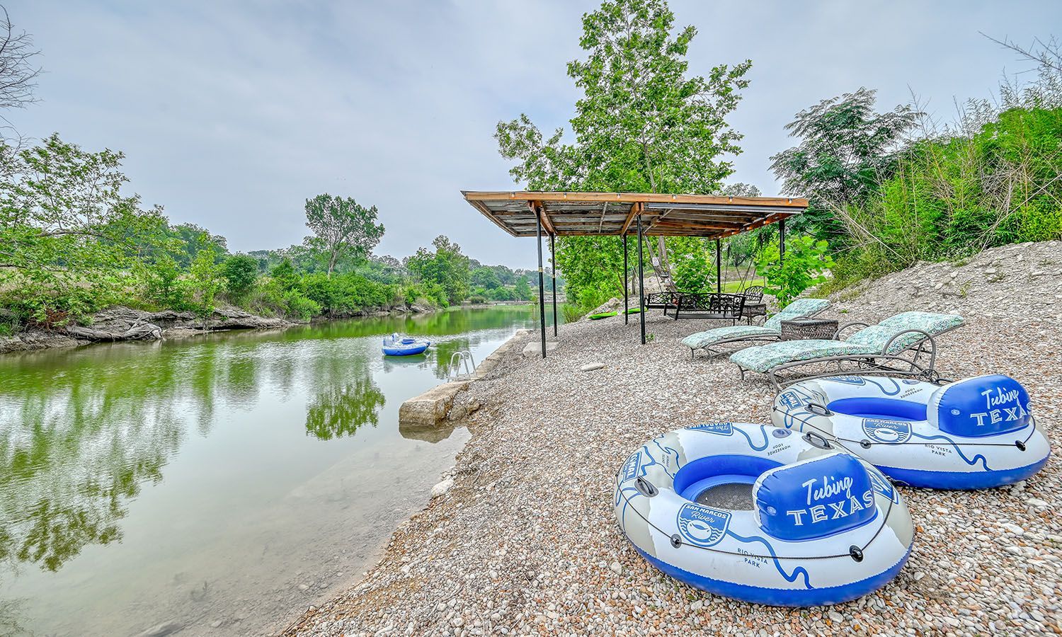 Two rafts are sitting on a rocky beach next to a river.