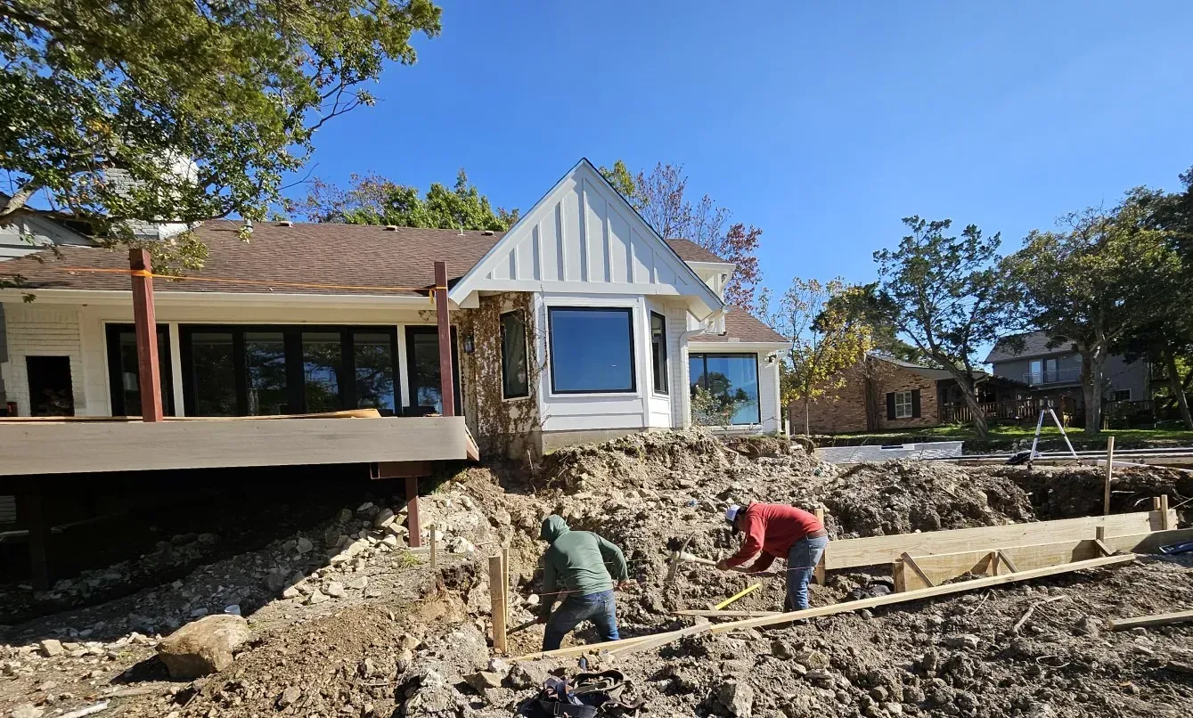 Workers excavating soil in front of a building under construction on a sunny day