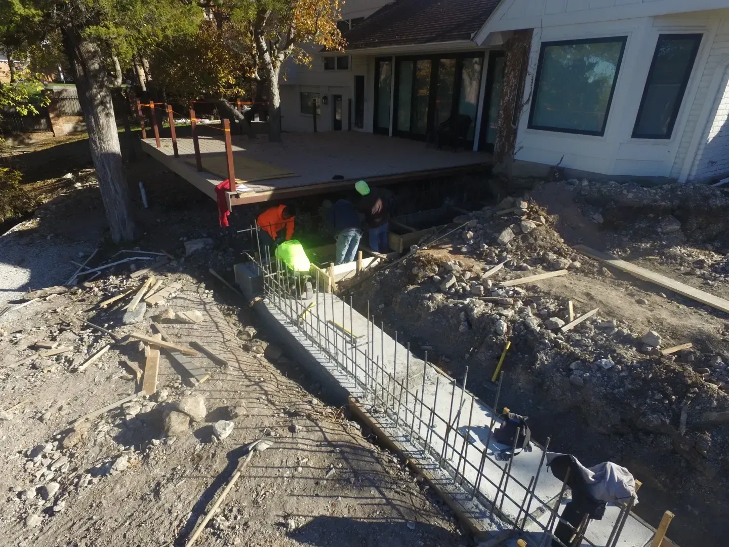 Construction workers pouring concrete for a house foundation beside a front porch