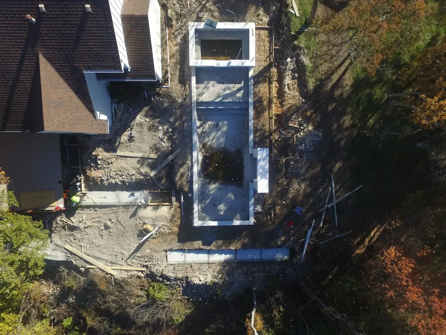 Aerial view of a house roof and patio surrounded by trees and winter debris.
