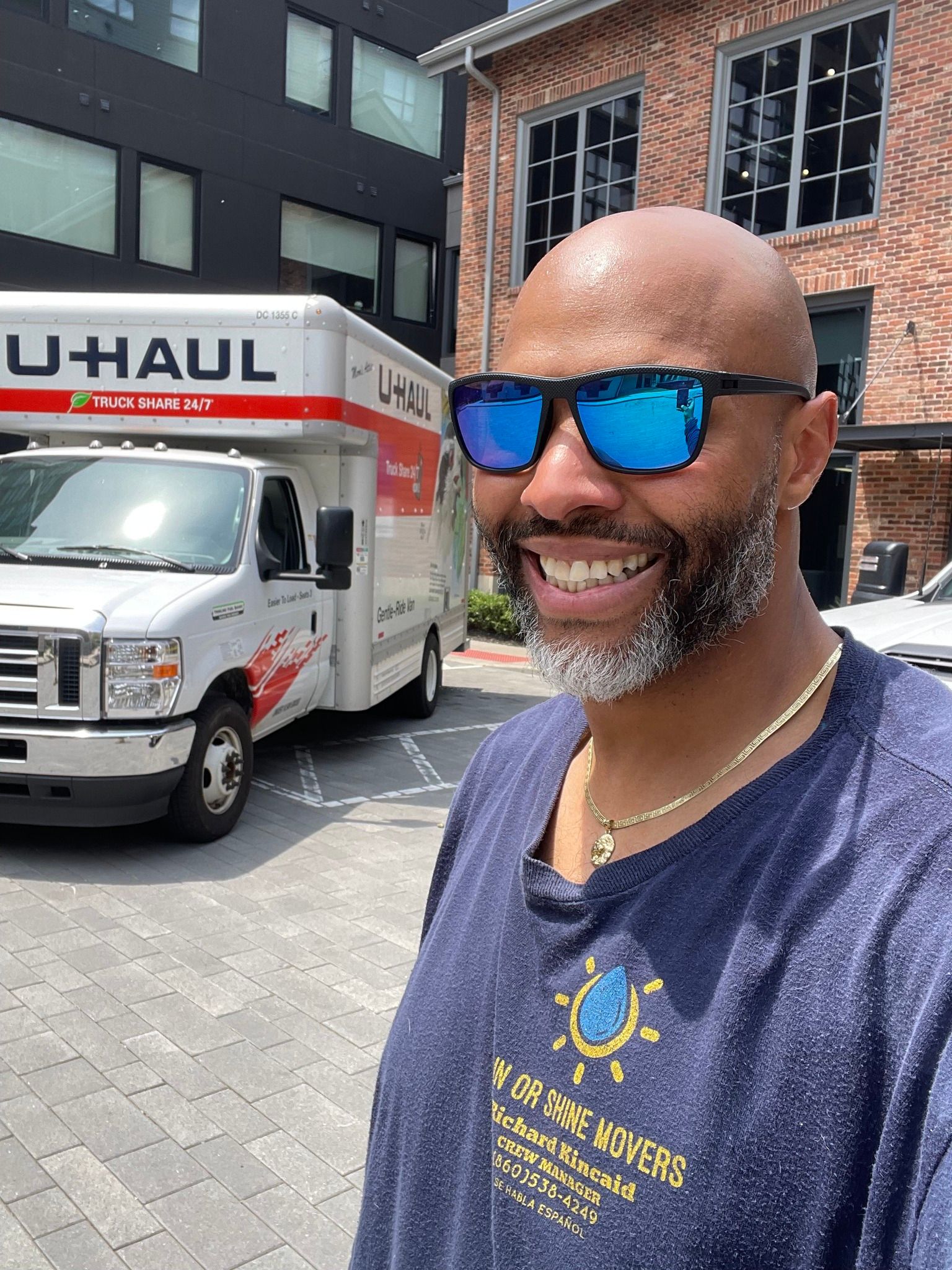 Man with sunglasses smiles near a U-Haul truck.