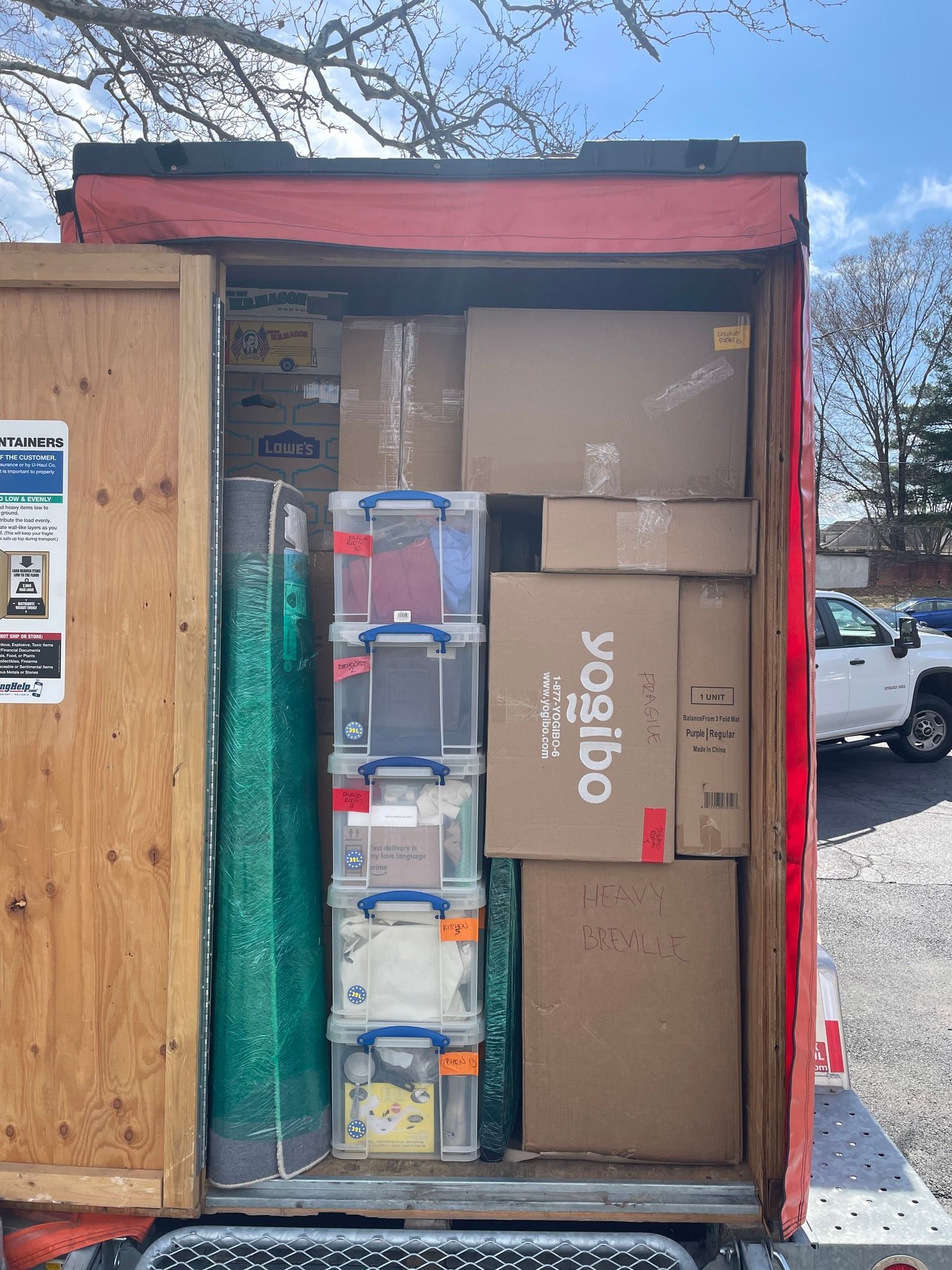Boxes and bins fill a moving truck, packed and ready to be transported.