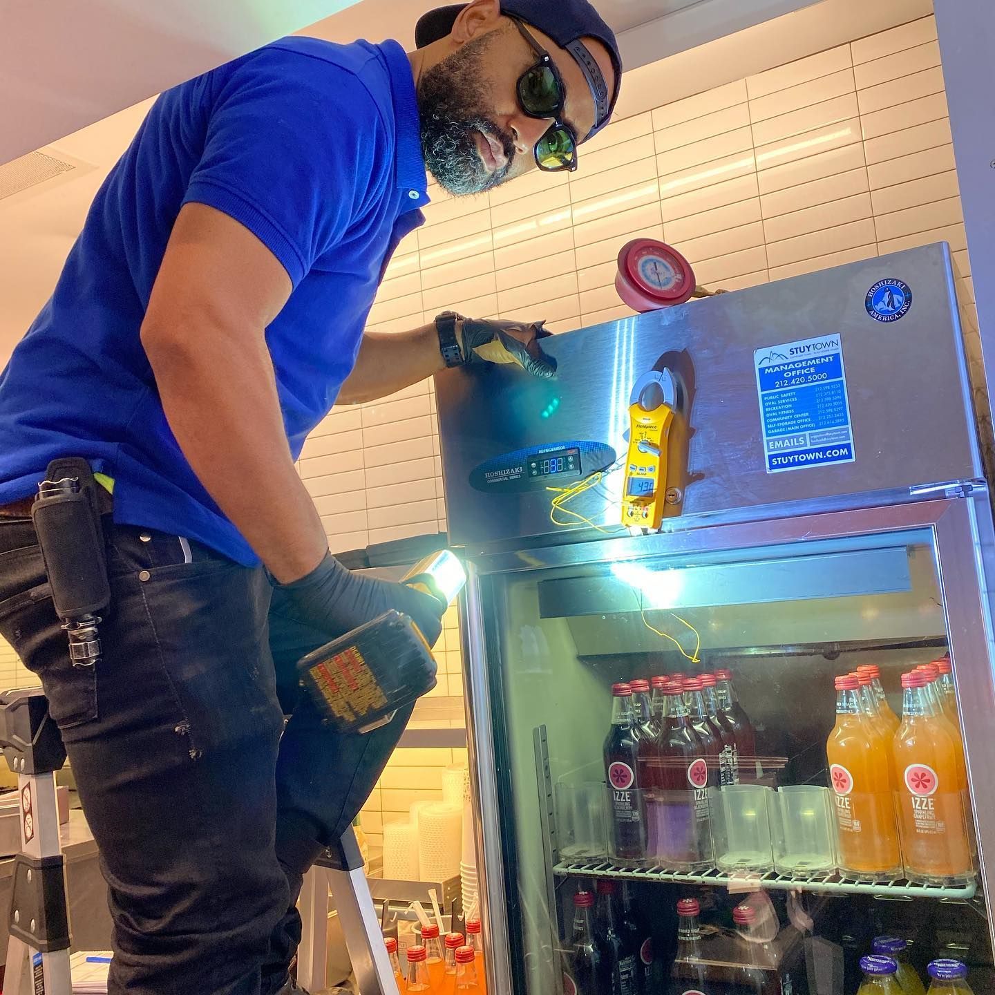 A man in a blue shirt is working on a refrigerator.