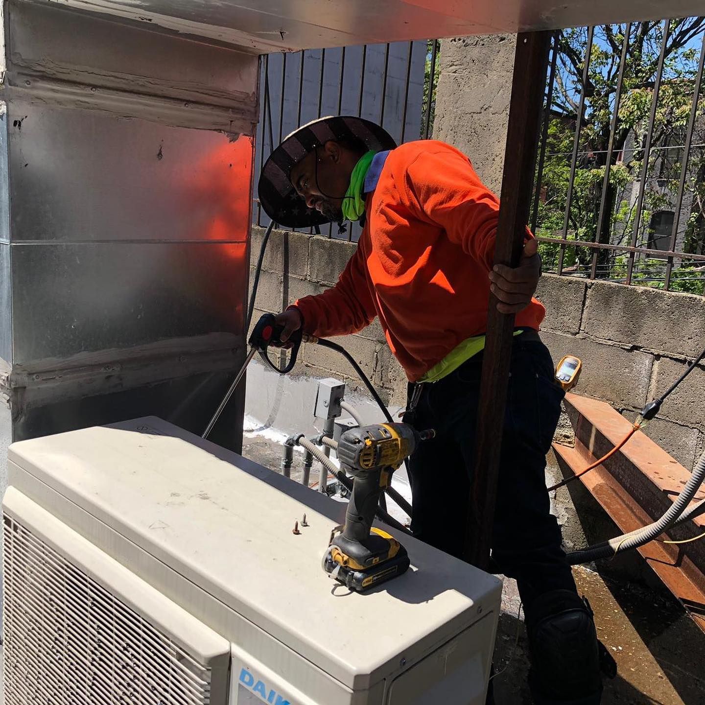 A man is working on a daikin air conditioner with a drill.