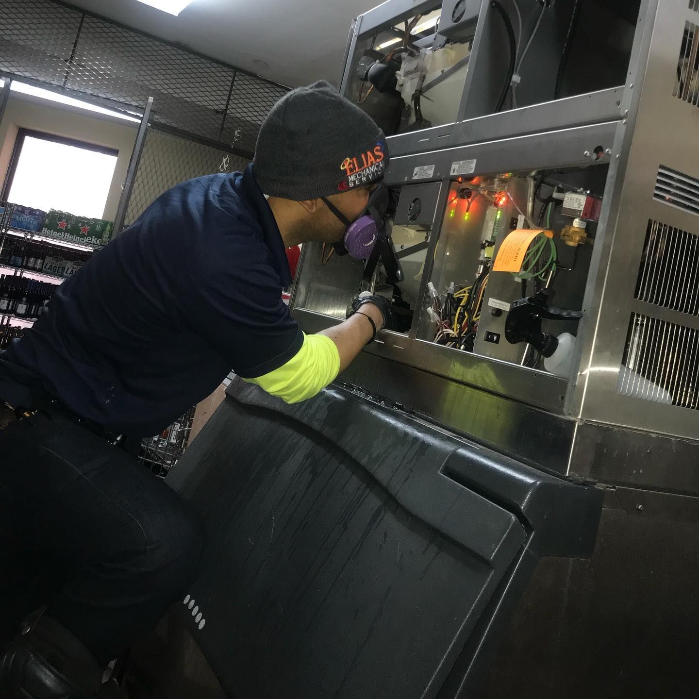 A man wearing a hat that says ' duke ' on it is working on a machine