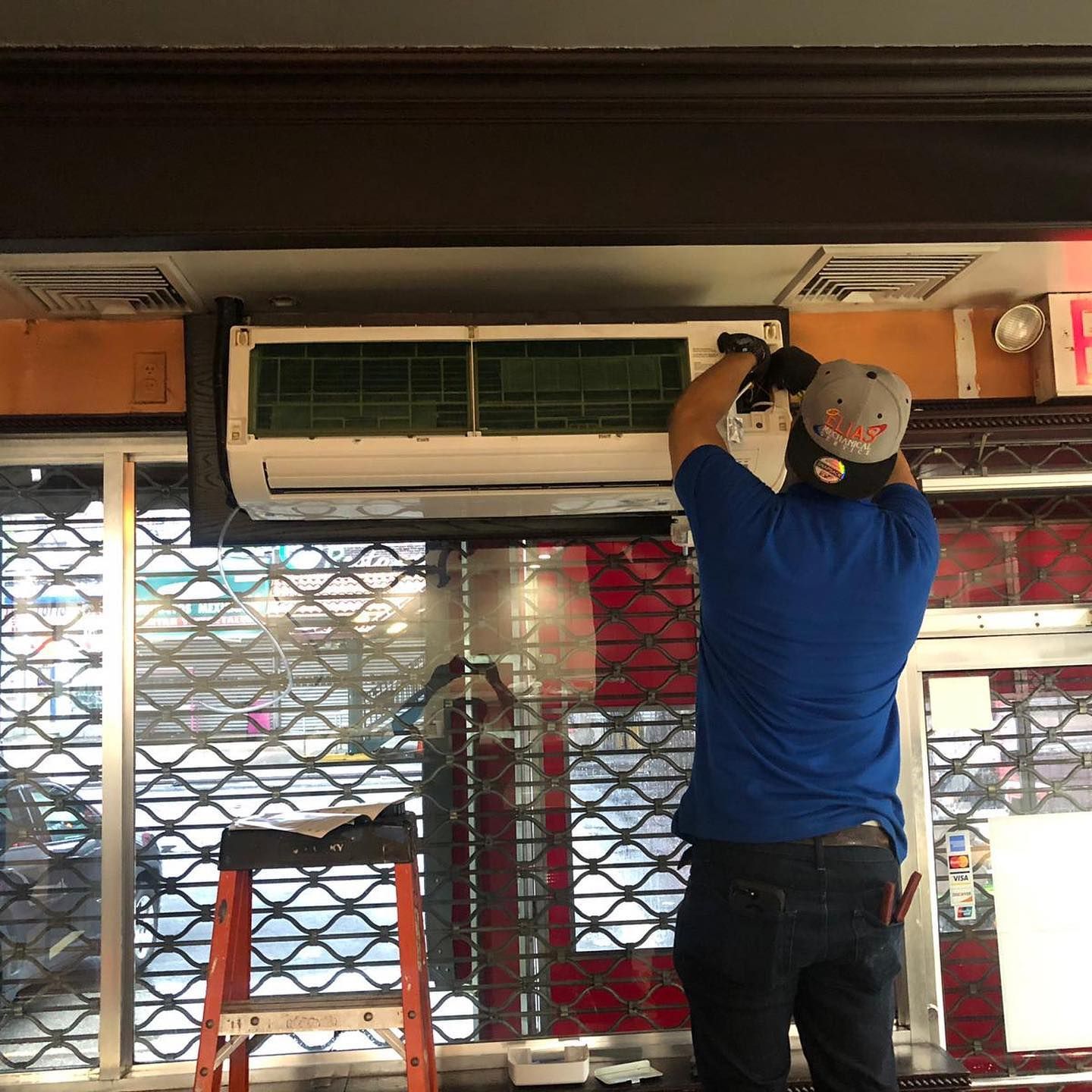 A man in a blue shirt is working on an air conditioner