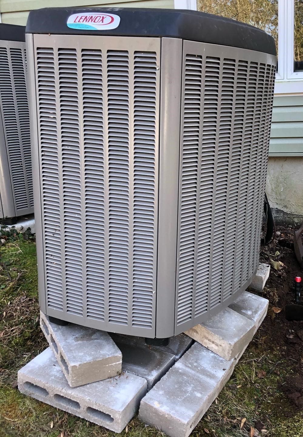A large air conditioner is sitting on top of a pile of bricks.