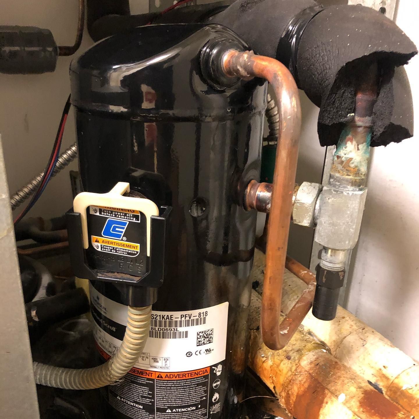 A close up of a compressor with a warning label on it