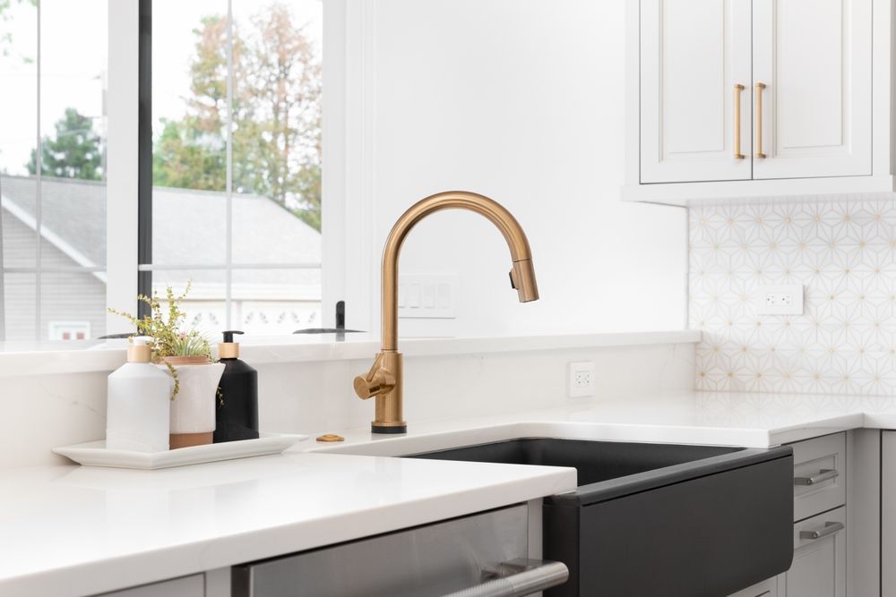 A kitchen with a black sink and a gold faucet.