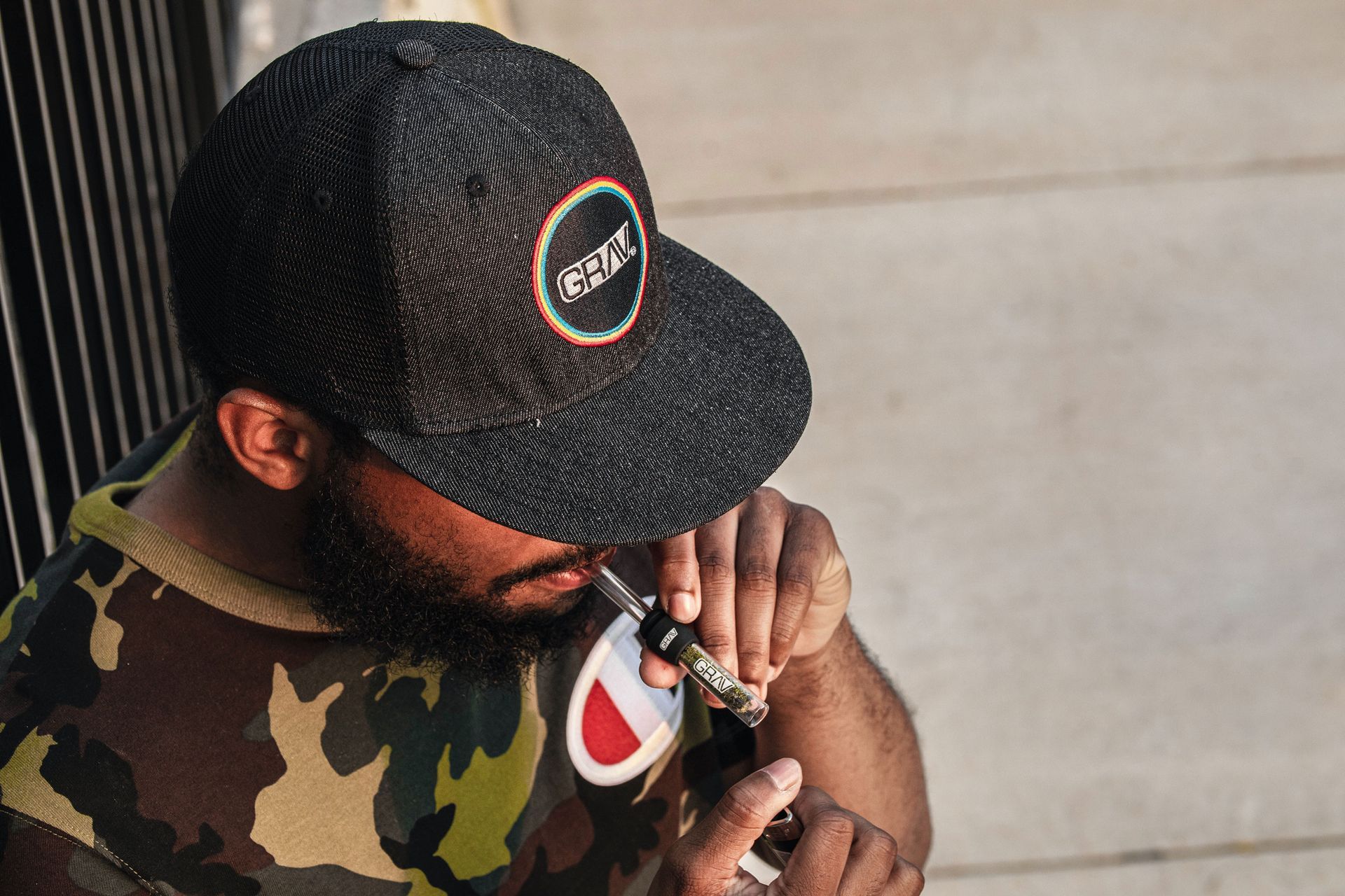 a man wearing a black hat taking drug in public