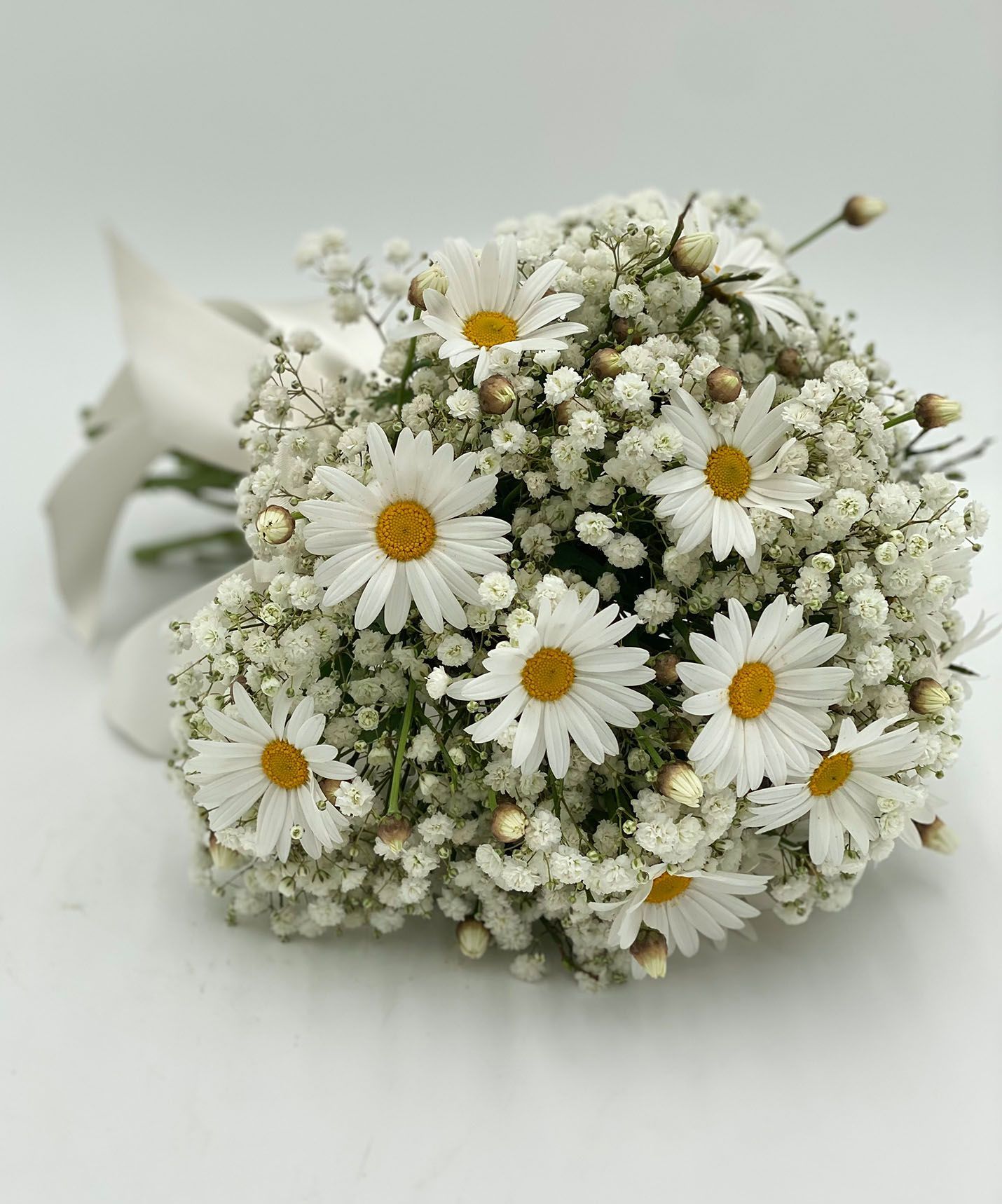 Ein Strauß Magariten und Schleierkraut auf einer weißen Oberfläche.