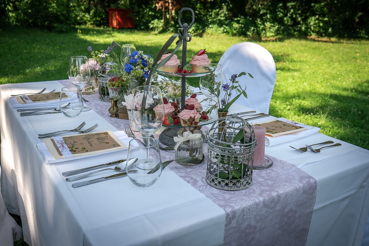 Im Gras ist ein Tisch für einen Hochzeitsempfang gedeckt.