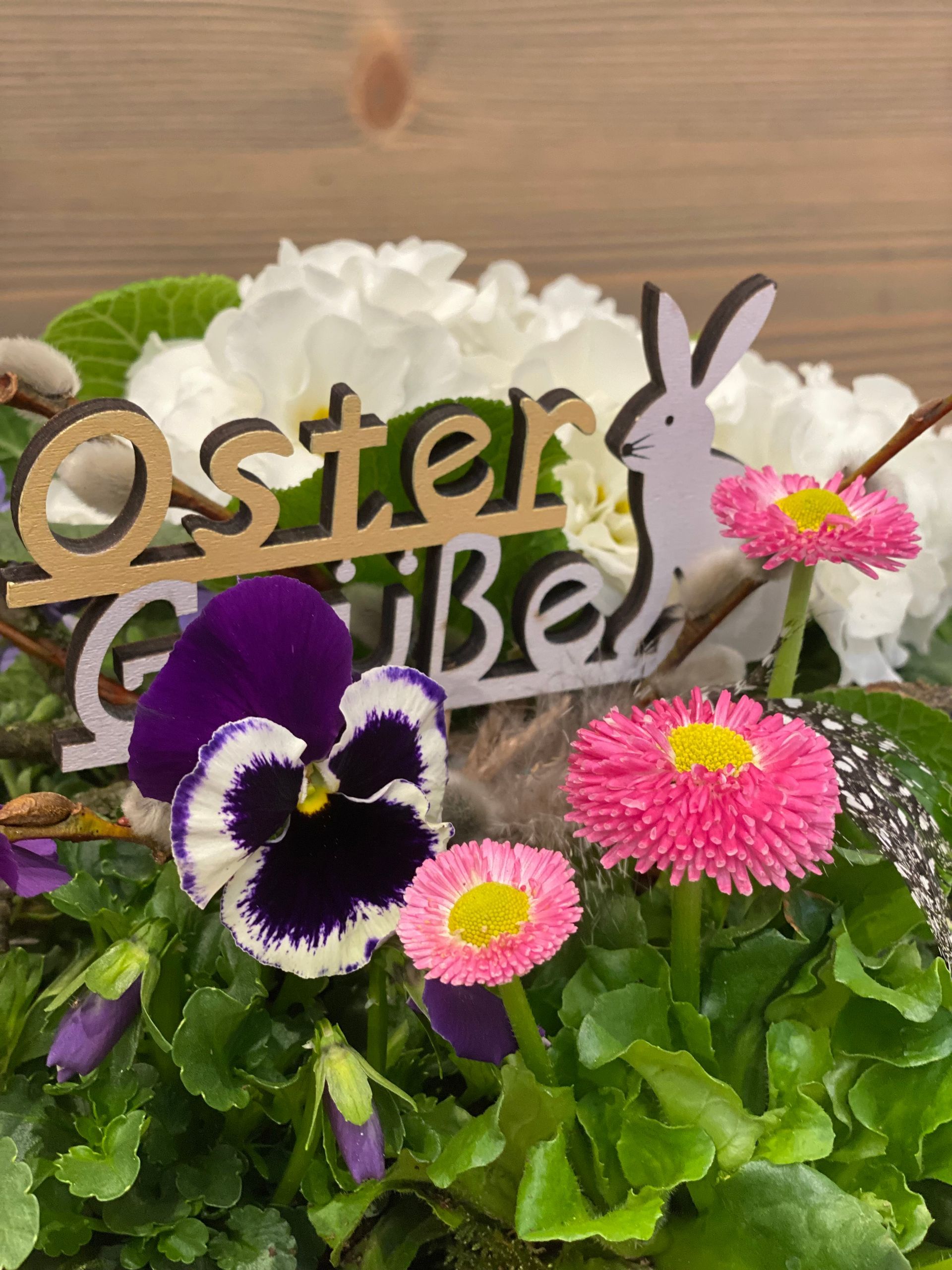 Auf einem Holztisch steht ein mit Blumen gefüllter Korb.