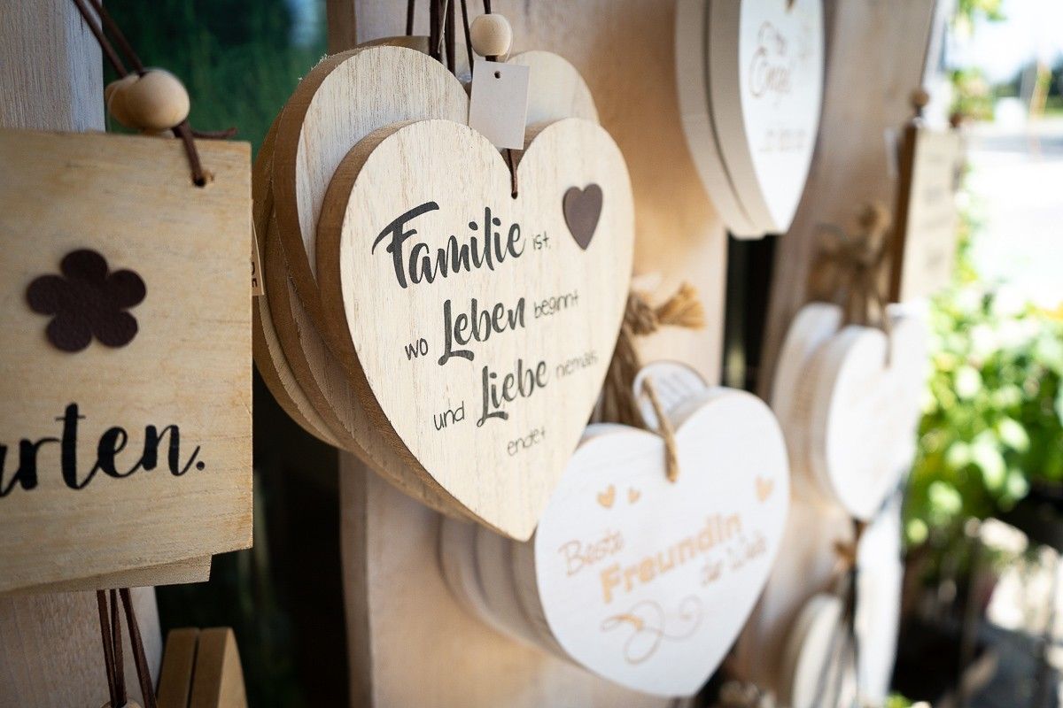 An einer Wand hängen einige Holzherzen.  Eines hängt mit dem Spruch  Familie ist wo Leben beginnt und Liebe niemals endet.