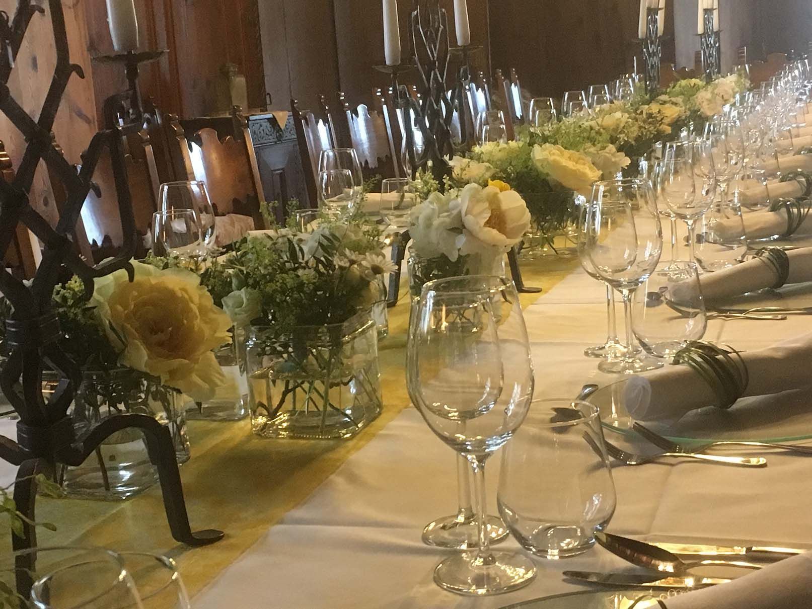 Ein für einen Hochzeitsempfang gedeckter Tisch mit Blumen und Kerzen darauf.