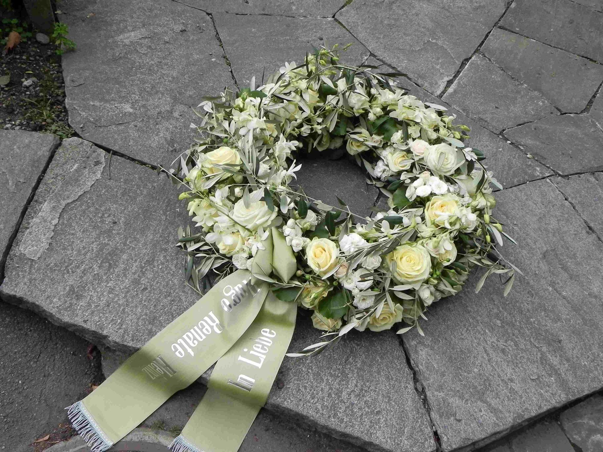 Ein Kranz aus weißen Blumen mit einem grünen Band darum