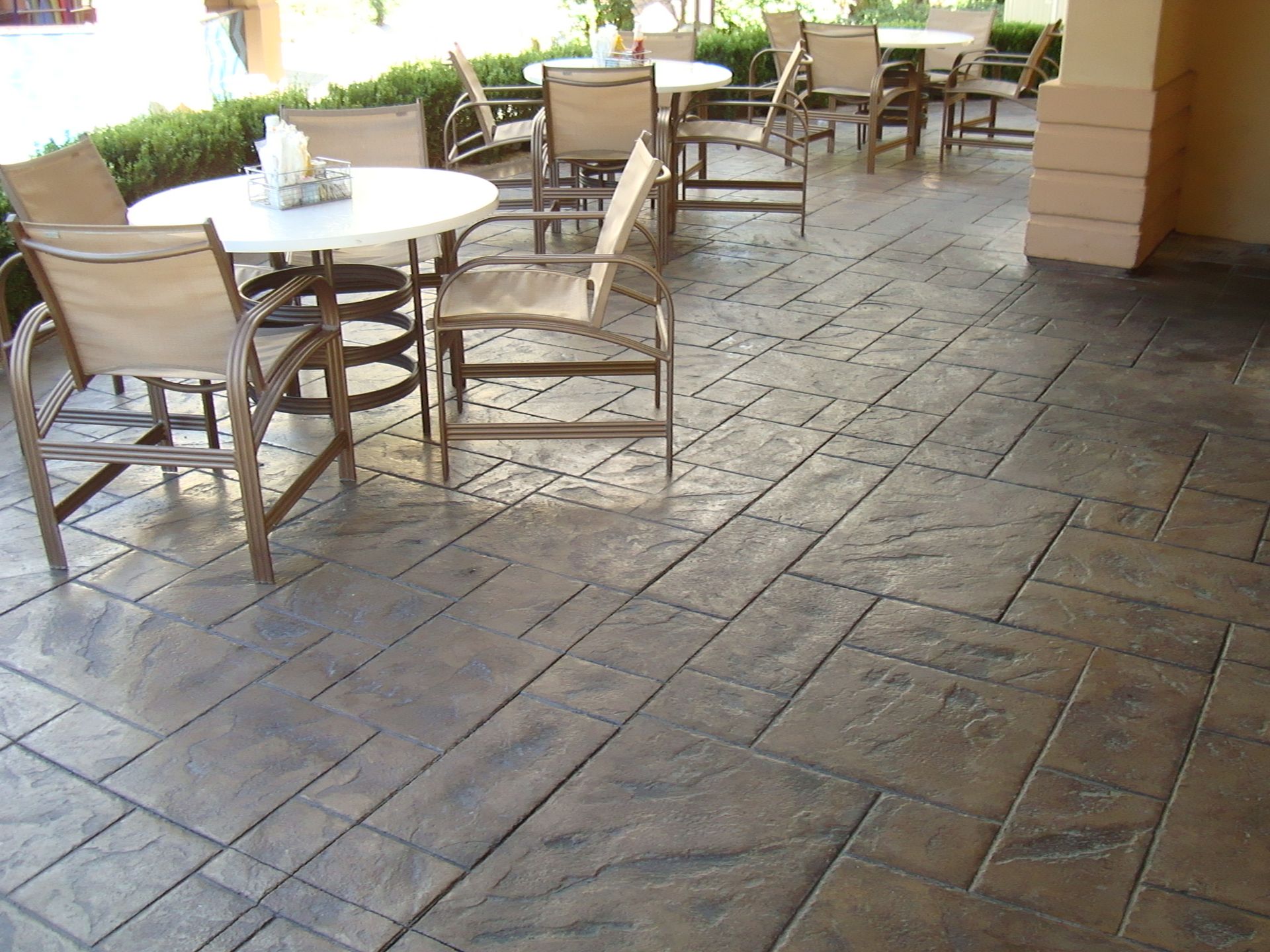 A patio with tables and chairs on stamped concrete