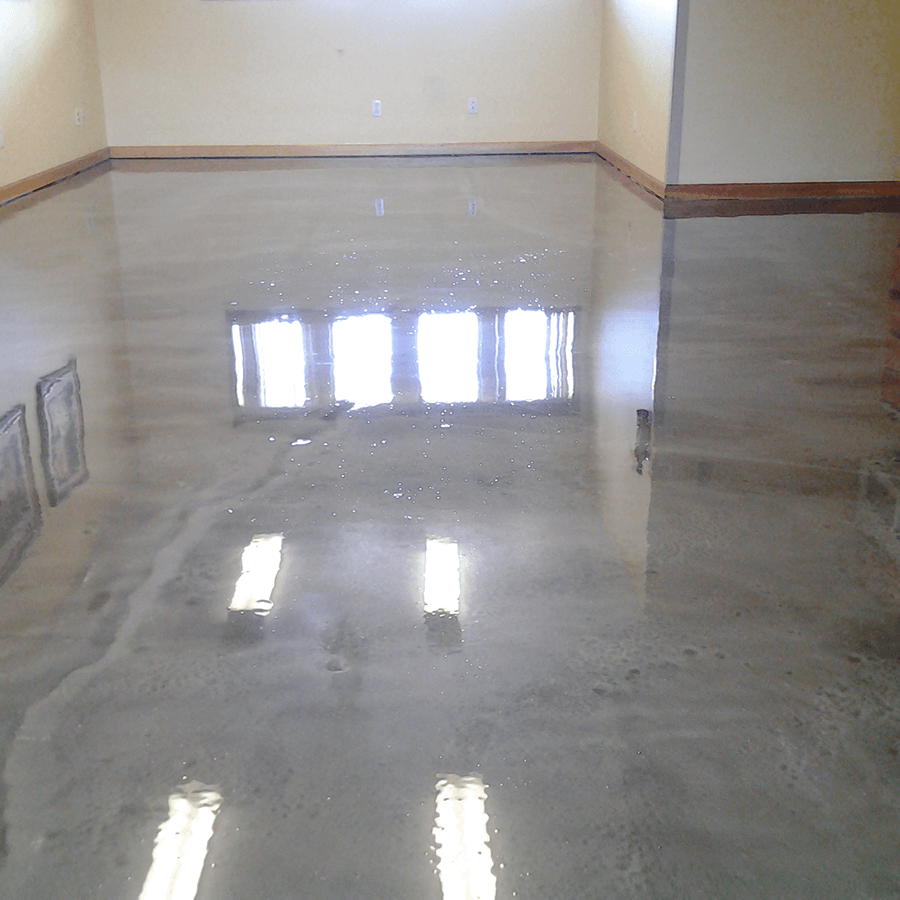 A shiny concrete floor in a room with a window reflected in it