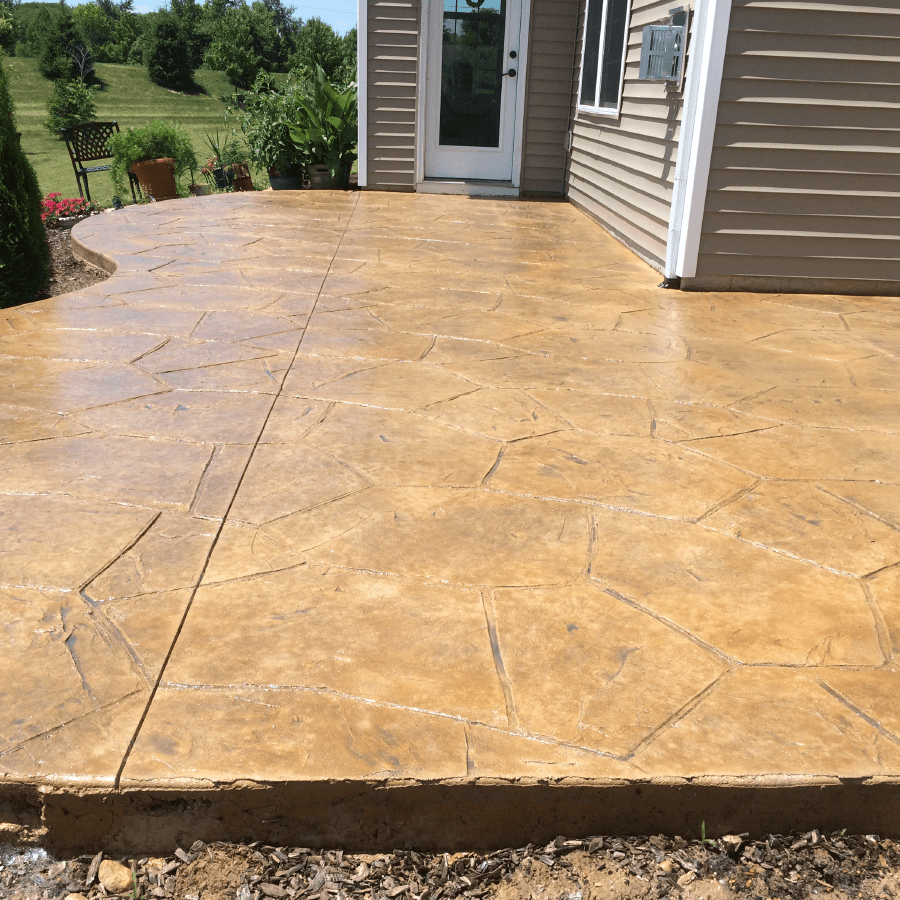 A stamped concrete patio in front of a house with a white door.