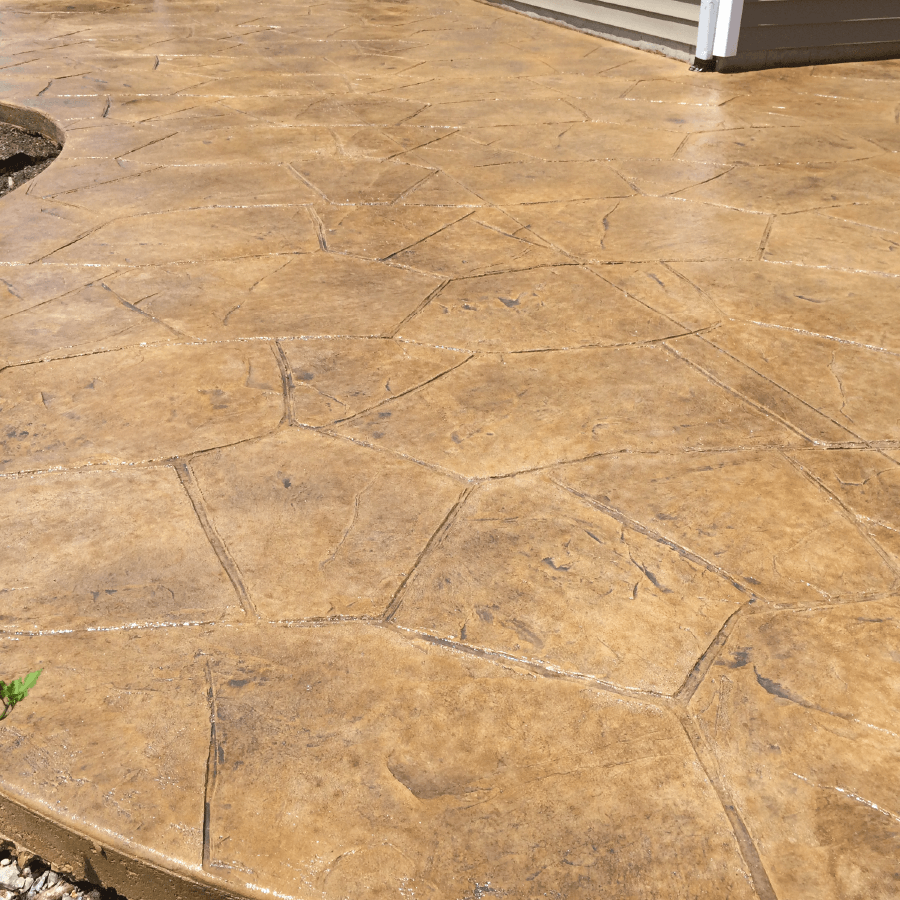 A close up of a stamped concrete patio with a house in the background.