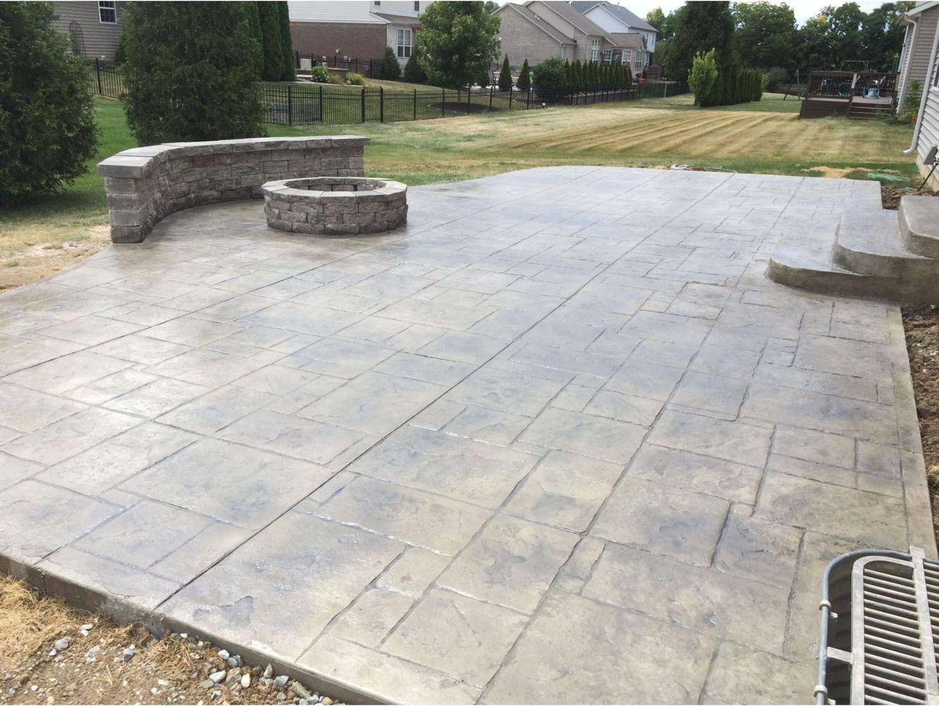 There is a fire pit in the middle of the decorative concrete patio.