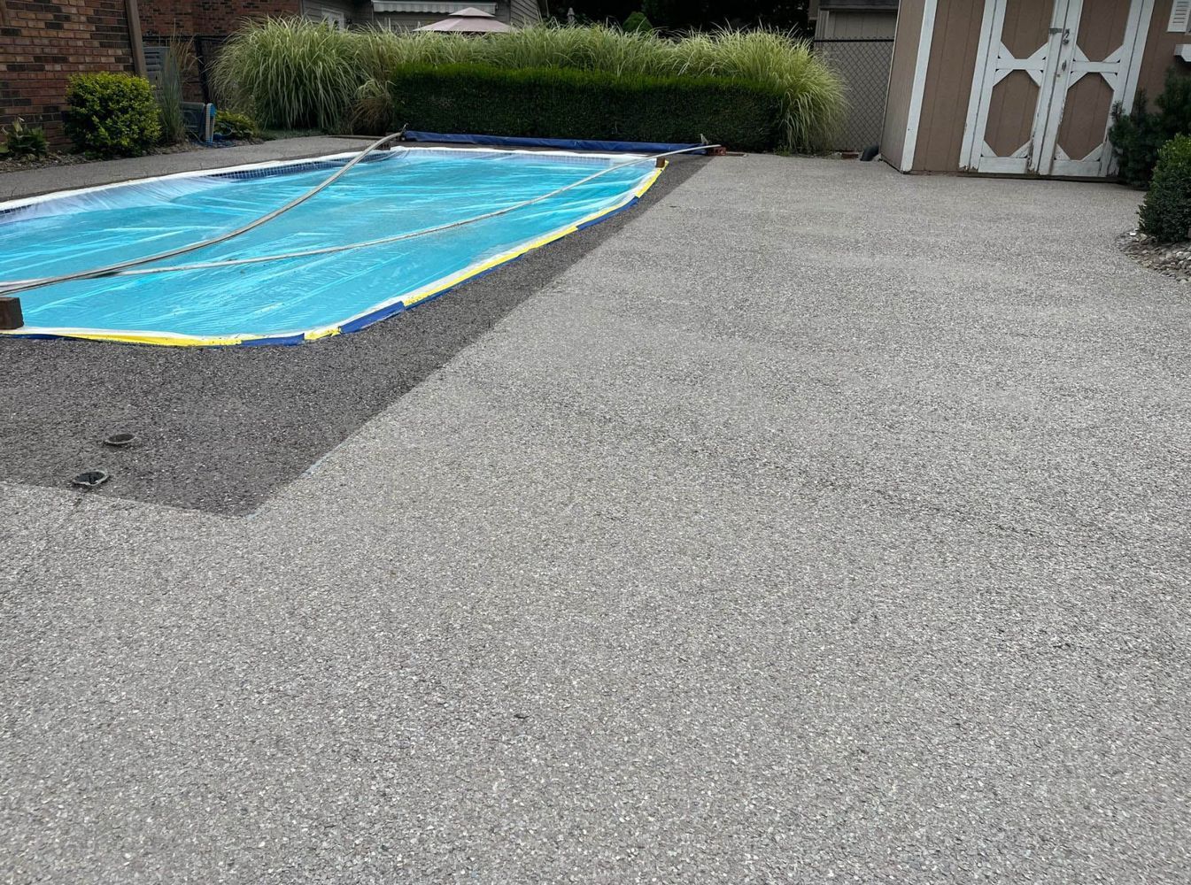 A swimming pool is surrounded by concrete next to a house.