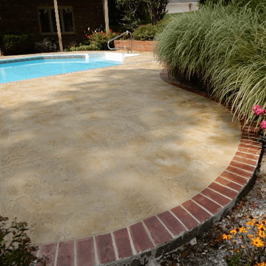 A swimming pool with stamped concrete and a decorative brick border around it
