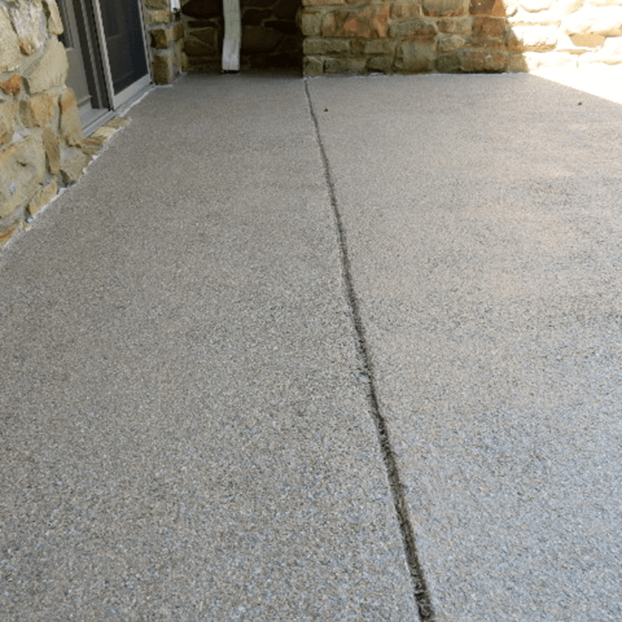 A concrete walkway with a stone wall in the background