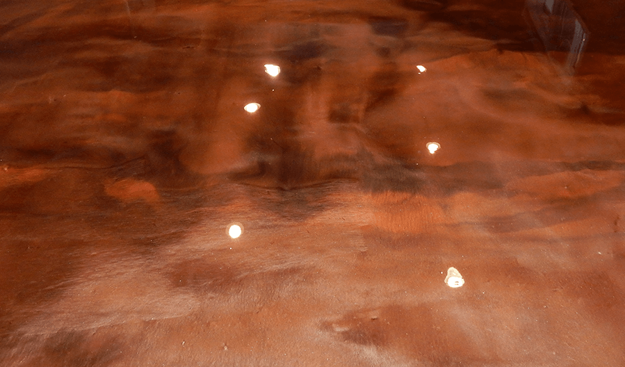 A close up of a copper colored floor with lights reflecting off of it.