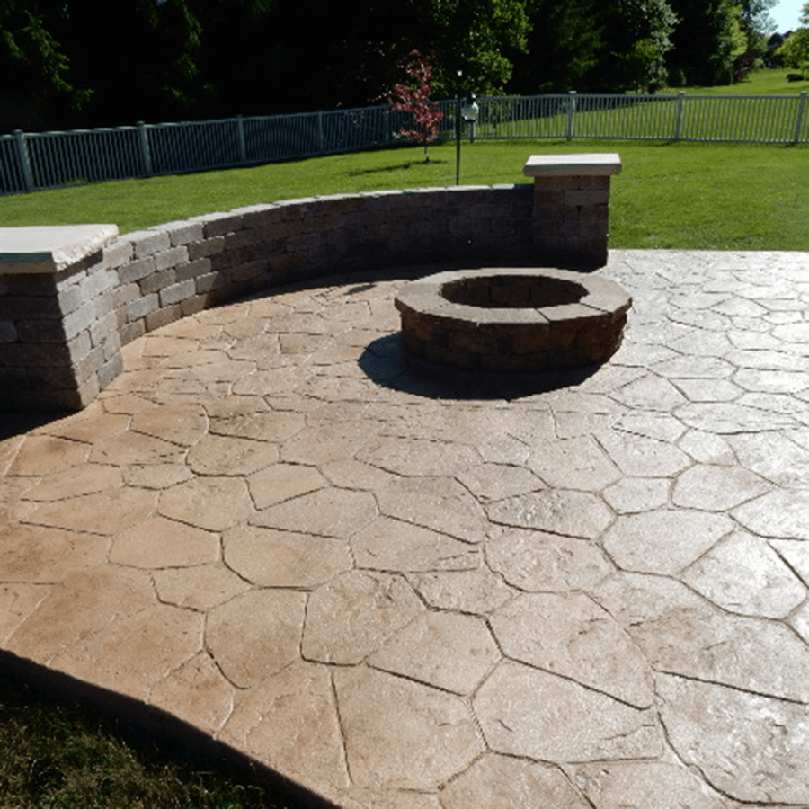 A decorative concrete patio with a fire pit in the middle