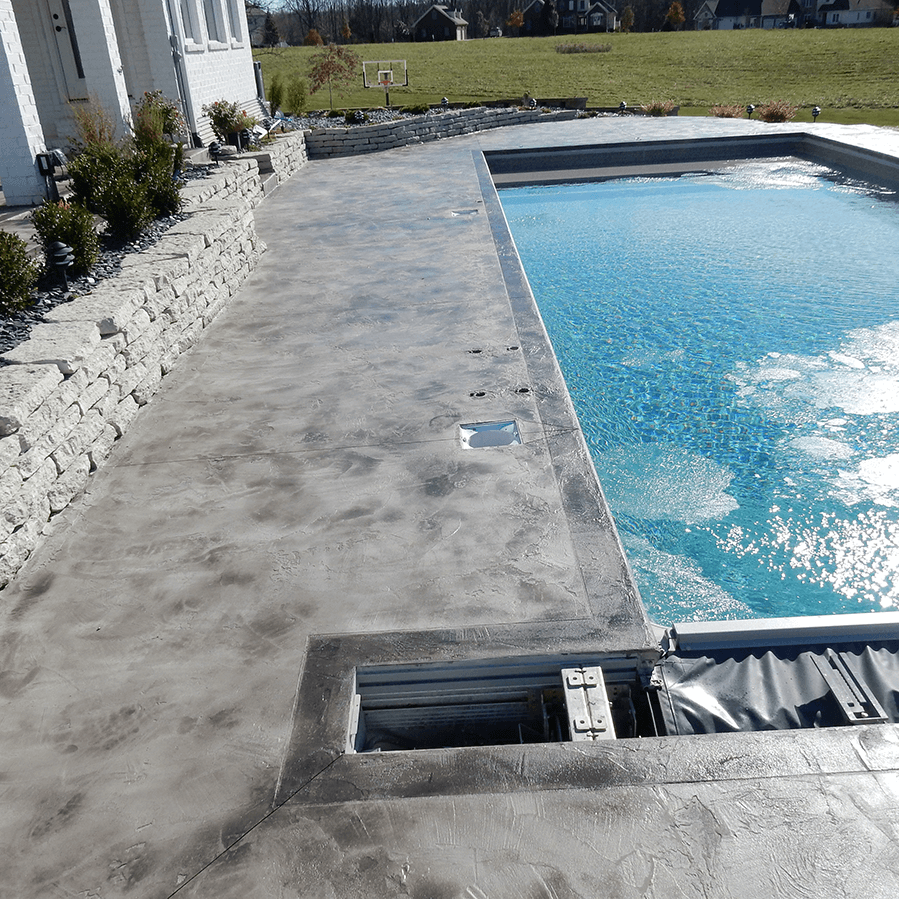 A large swimming pool is surrounded by a decorative concrete walkway