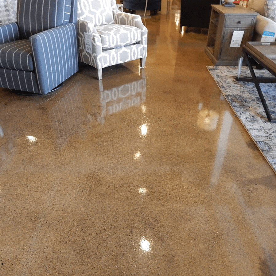 A living room with chairs and a coffee table on a shiny concrete floor