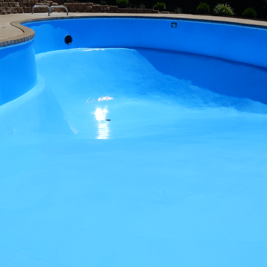 A blue swimming pool surrounded by decorative concrete