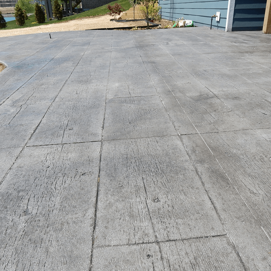 A concrete driveway with a blue house in the background