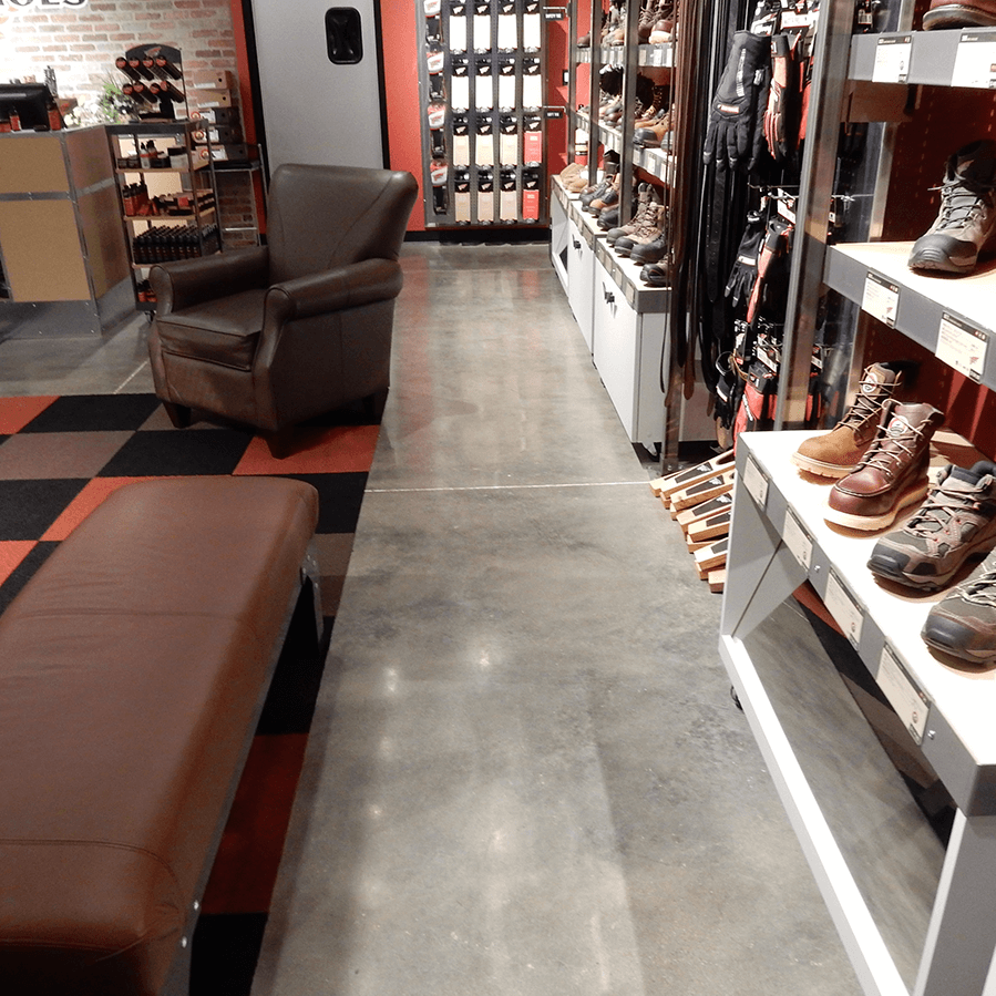 A store filled with lots of shoes and a chair on a shiny concrete floor
