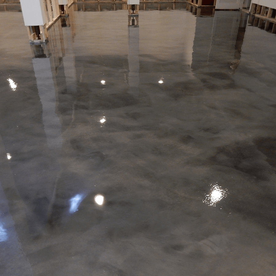 A shiny concrete floor with a reflection of lights in it