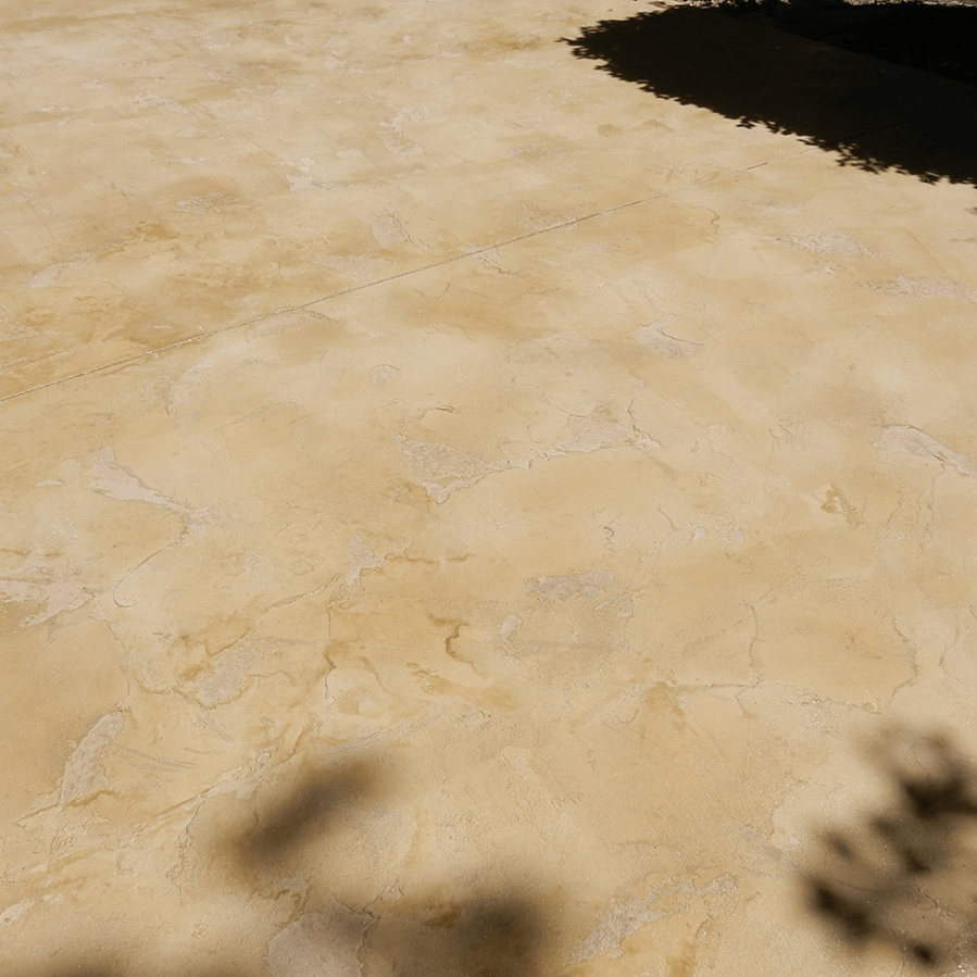 A shadow of a tree is cast on a stamped concrete patio.