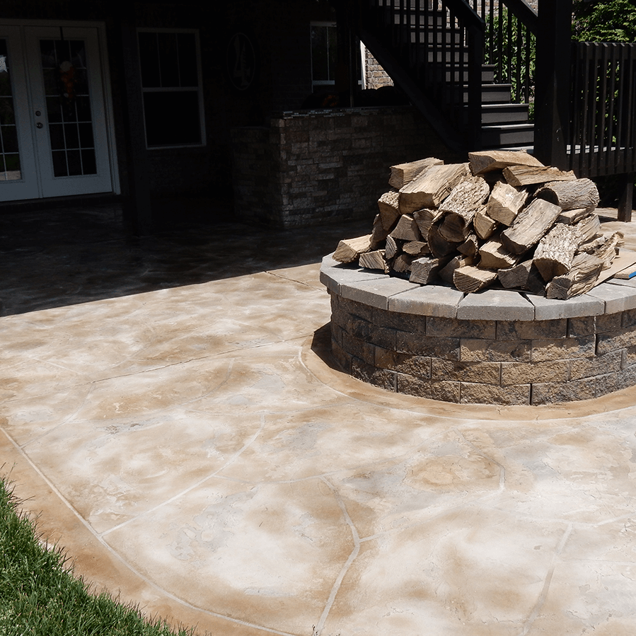 A fire pit with a pile of logs in it on a decorative concrete patio