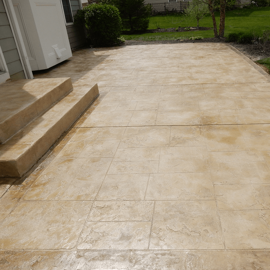 A decorative concrete driveway with steps leading to a house