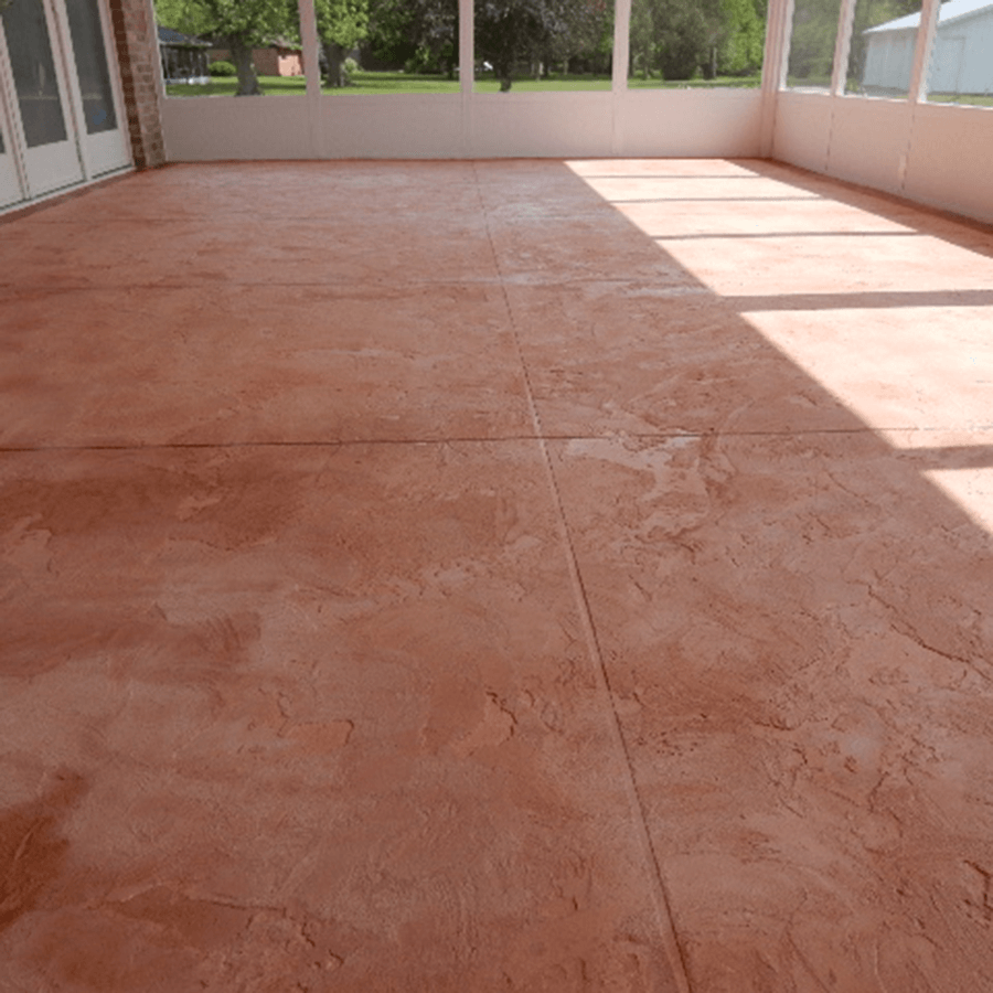 A large patio with a red stamped concrete floor and a lot of windows.