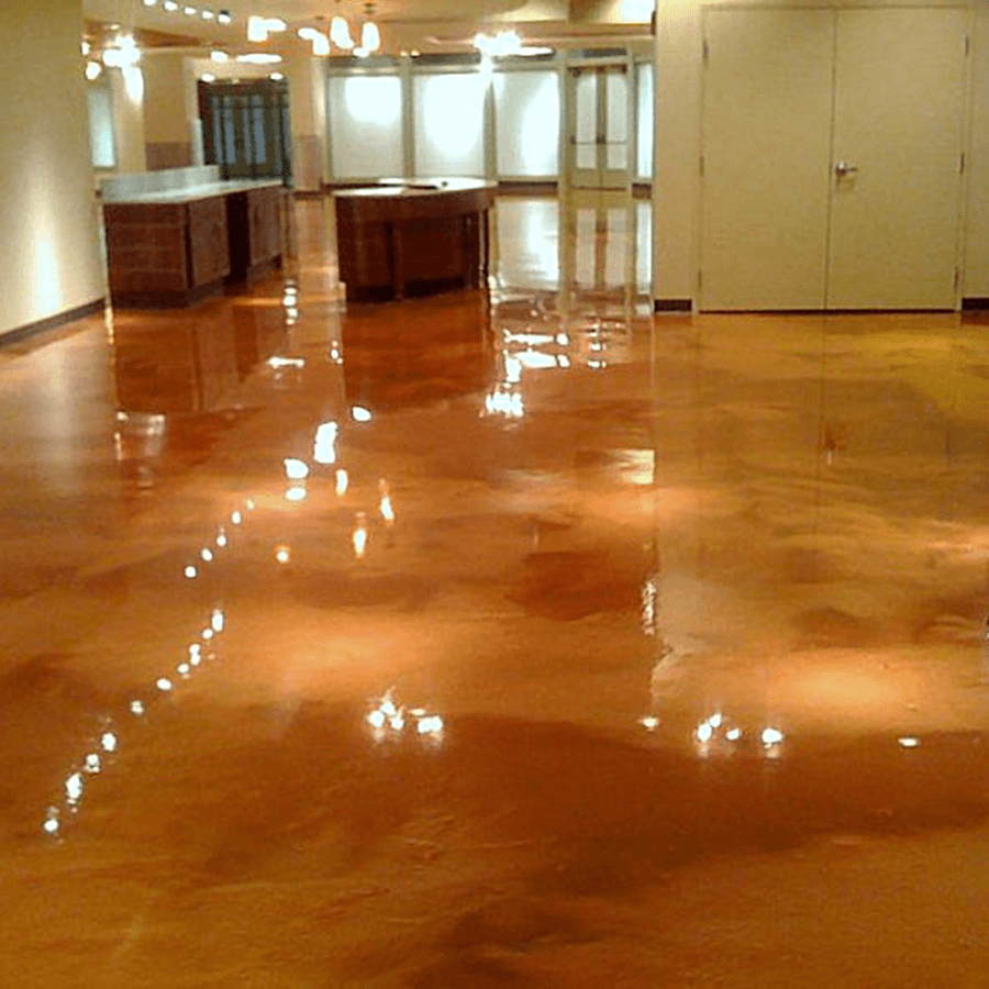 A large room with a shiny concrete floor and a kitchen in the background.