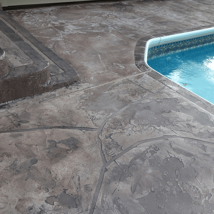 A swimming pool is surrounded by a stamped concrete deck